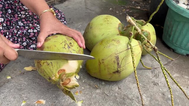 Shaving the shell of a fresh green young coconut