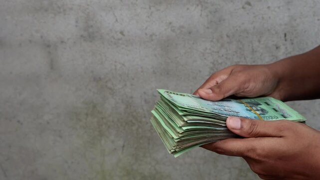Close Up Shot of Female Hands Holding and Displaying Folded Bundle of Bangladeshi Paper Money - Microcredit Loan, Savings, Financial Growth, and Wealth Concept