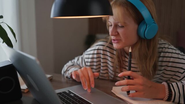 Teenage student procrastinating on homework by singing along to music while wearing headphones and using laptop, illustrating distraction, lack of focus and study difficulties.
