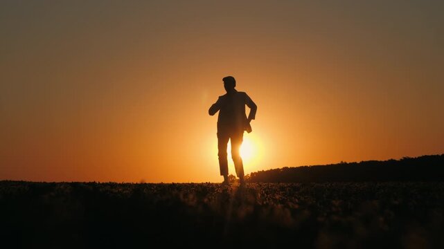 Female Farmer Dancing in Silhouette Across Field at Sunset