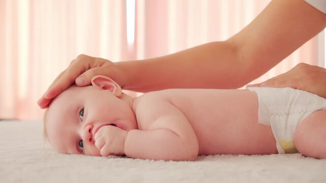 Masseuse doing massage on a healthy infant baby. Small caucasian newborn laying on his belly while masseuse is performing a massage for his small back and developing muscles.