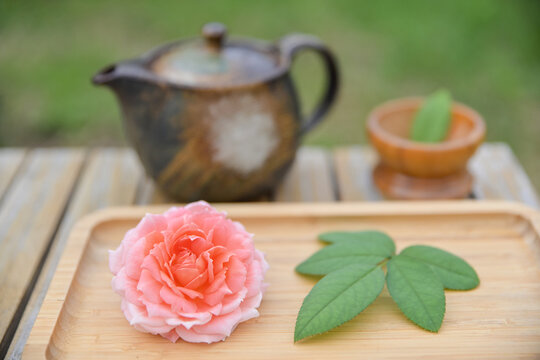 fresh rose tea setup, wooden tray, and teapot on a bamboo surface. wellness lifestyle concept.