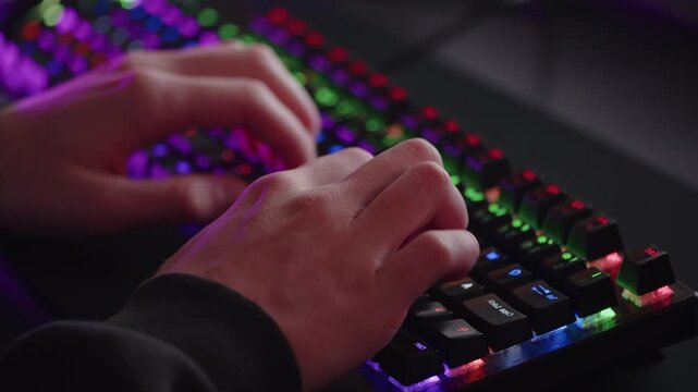 Male hands is typing on the computer keyboard, close up view. Fast typing on the black gaming keyboard. Fingers typing on the led rgb keyboard in the dark room. Cinematic 4k footage in real time.