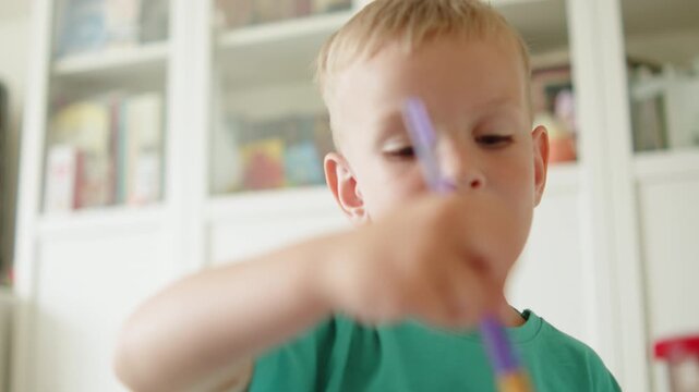  Child painting with a brush and paint. Closeup of a little kid practicing art. Adorable boy developing drawing skills in his room. Kindergartner education concept.