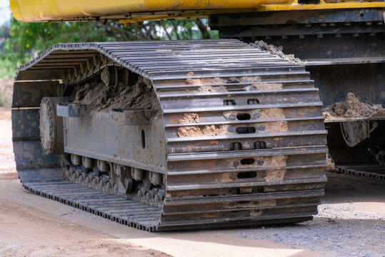 Close view of heavy excavator steel tracks covered dirt at construction site showing durable crawler machinery used for earthmoving excavation work