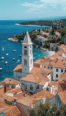 Fototapeta premium sunlit coastal town with terracotta roofs and stone church tower overlooking turquoise sea and sailboats, evoking peaceful seaside charm