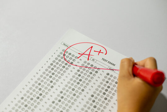 Education and assessment concept, teacher grading student exam with top mark.