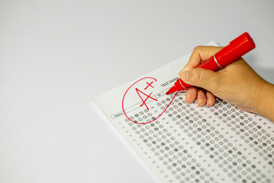 Education and assessment concept, teacher grading student exam with top mark.