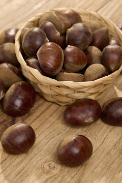 Fresh Chestnuts in a Woven Basket on Wood