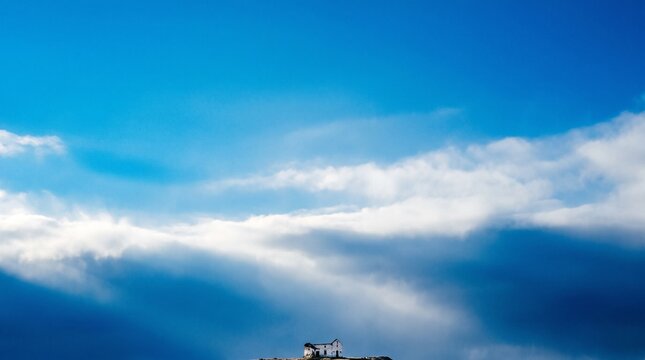 Minimalist Tiny House under Vast Blue Sky and White Clouds