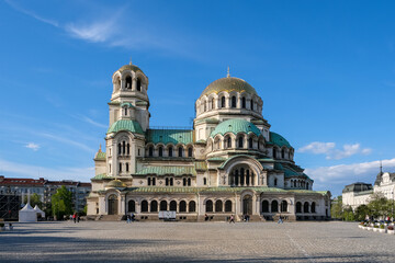 Fototapeta premium Sofia, Bulgaria – Angular exterior view of Alexander Nevsky Cathedral, showing its gold-plated dome and green copper roofs against blue sky.