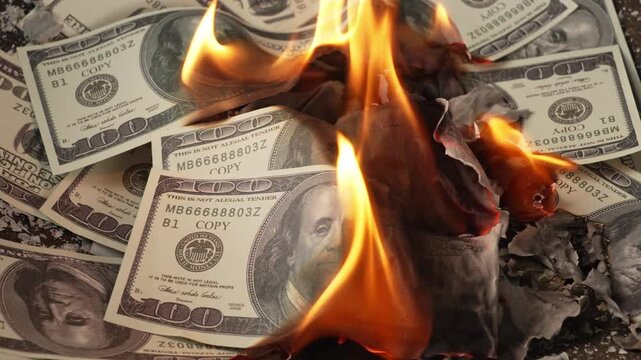 Burning prop 100‑dollar US banknotes with flames and ash debris
