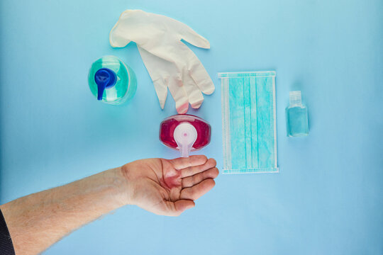 The concept of coronavirus COVID-19, How to protect yourself from infection. Handwash is squeezed onto the hand, mask and tablets. Flat lay on a blue background.