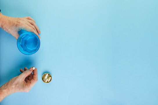 The concept of coronavirus COVID-19, How to protect yourself from infection. Pills for infection and a glass of water. Flat lay on a blue background.