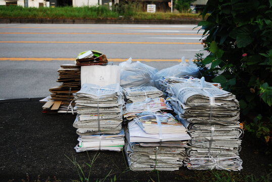 路上に積み上げられた資源ごみの古紙と新聞紙