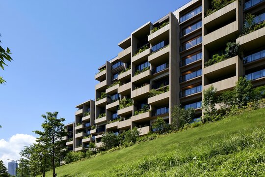 青空広がる都会の傾斜地に建つ緑豊かなモダンデザインマンション