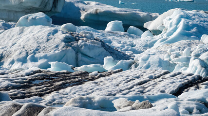 Close-up view of icebergs from Vatnajokull glacier drifting across Jokulsarlon lagoon, Iceland, highlighting beautiful ice textures and abstract shapes in summer landscape. © Asanee