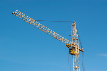 Yellow construction tower crane against clear blue sky © Dmitry