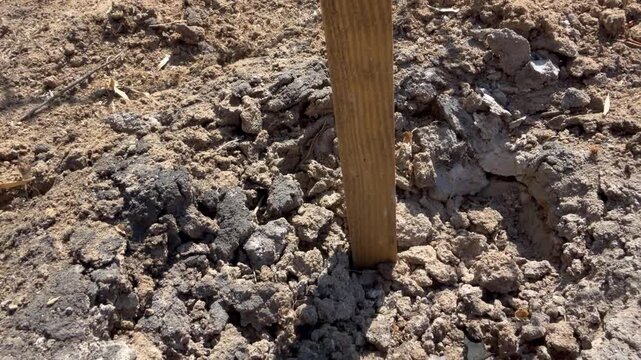 Crater and metal fragments after controlled detonation of a 3B30 cluster submunition on a demining site, marked by a picket. The Cyrillic label 3Б30 reads 3B30 in English