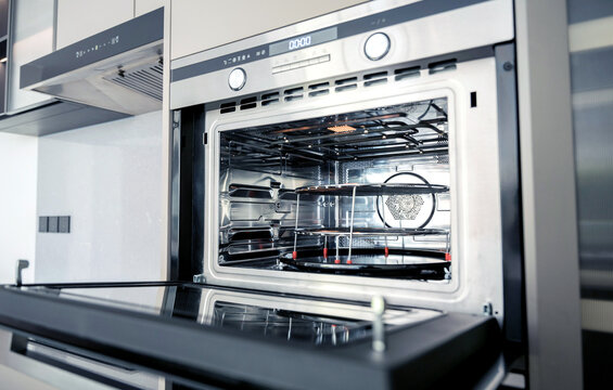 Open stainless oven interior with tray, clean metal rack and reflective glass door, warm lighting