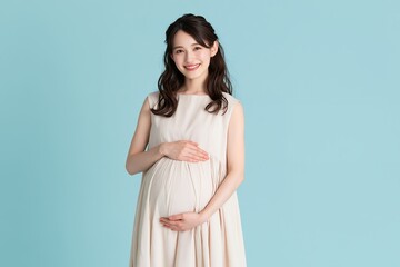 Fototapeta premium 優しい笑顔の日本人妊婦が膨らんだお腹に手を当てるマタニティ