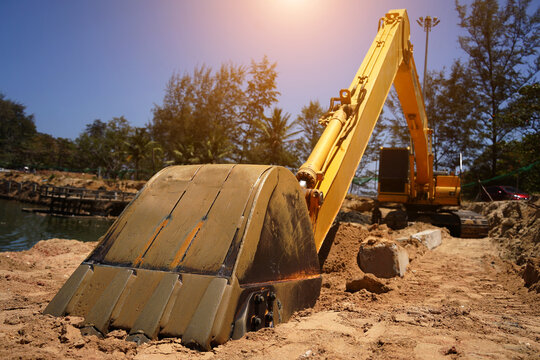 Building process city levee. Excavator dredging pond bank