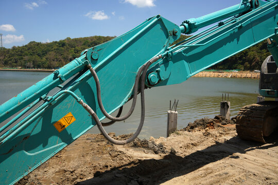 Building process city levee. Excavator dredging pond bank