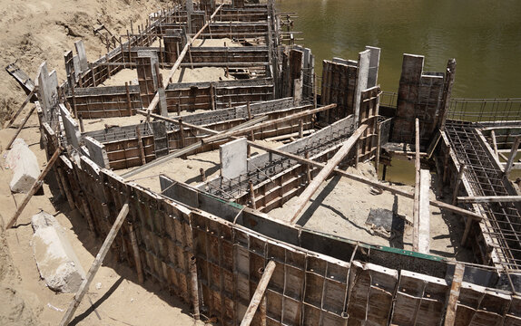Building process city levee. Exposed foundation rebar grid at site, standing formwork and concrete footings