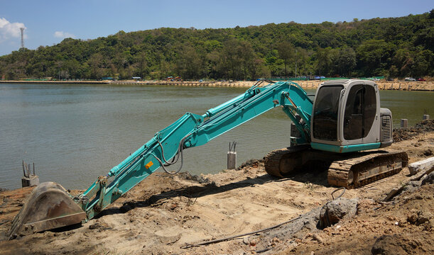 Building process city levee. Excavator dredging pond bank