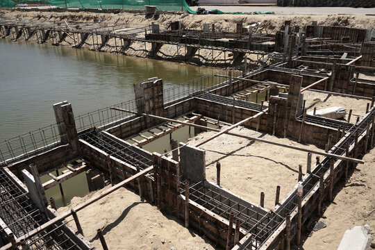 Building process city levee. Exposed foundation rebar grid at site, standing formwork and concrete footings