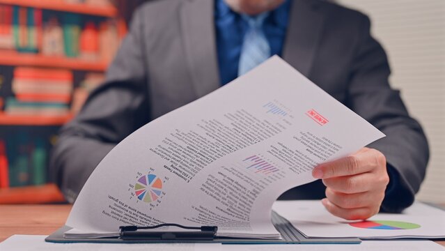 Executive conducts financial analysis reviewing corporate data, managing thorough analysis over document pages as manager completes financial analysis.