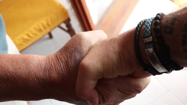 Close-up of a younger man with tattoos shaking hands with an older man, symbolizing intergenerational connection, respect, agreement, and the passing of experience between different ages