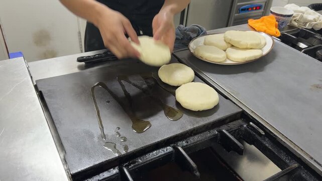 Chef cooking colombian arepas on a griddle