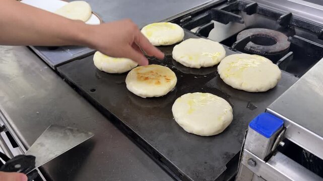 Chef cooking colombian arepas on a restaurant griddle