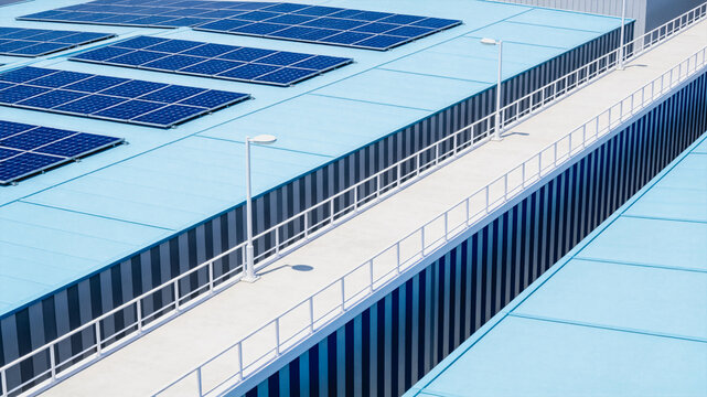 Photovoltaic solar panels are installed on a light blue building rooftop, with a walkway and railings alongside.