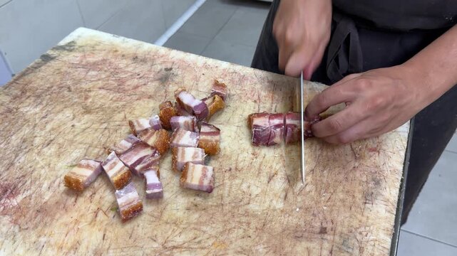 Chef cutting crispy pork belly and deep frying croquettes