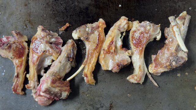 Grilled lamb chops sizzling on a hot plate