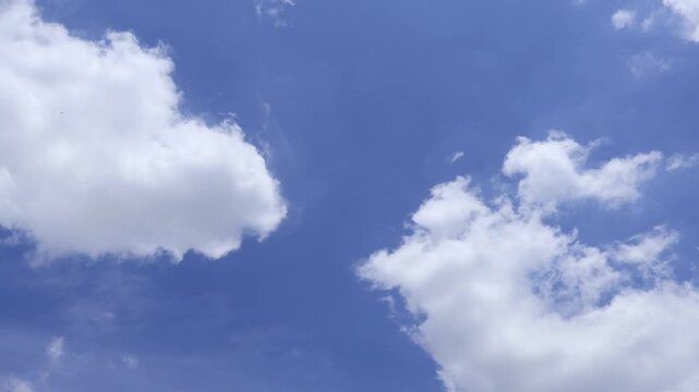 A jet airplane flying through white clouds leaving a long distinct contrail in bright blue sky