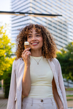 Smiling woman enjoying ice cream cone outdoors in city