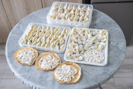 Frozen handmade dumplings and noodles are laid out on the table.