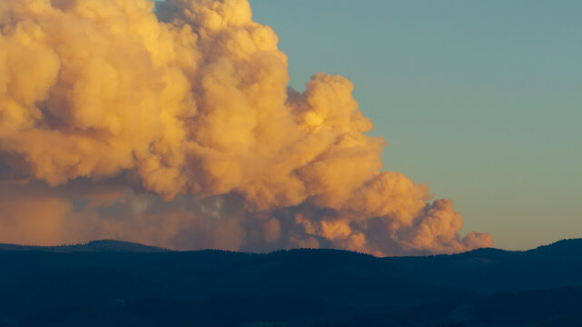 Massive smoke plume from wildfire over hills