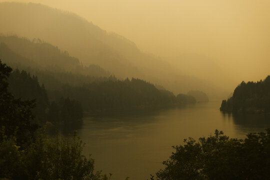 Hazy river flowing through layered forested mountains at dusk