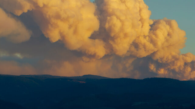 Golden smoke clouds billow over a dark mountain range