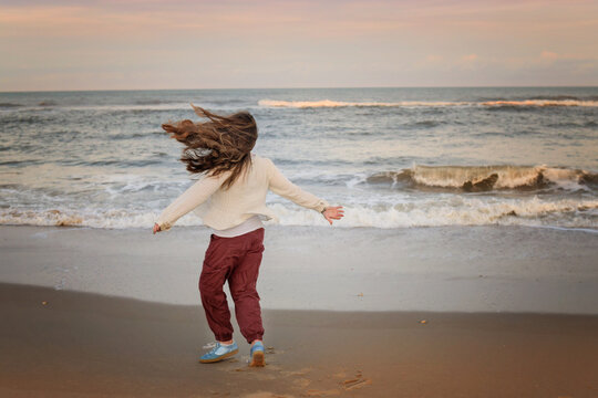 Girl spinning on the beach with her hair flying in the wind