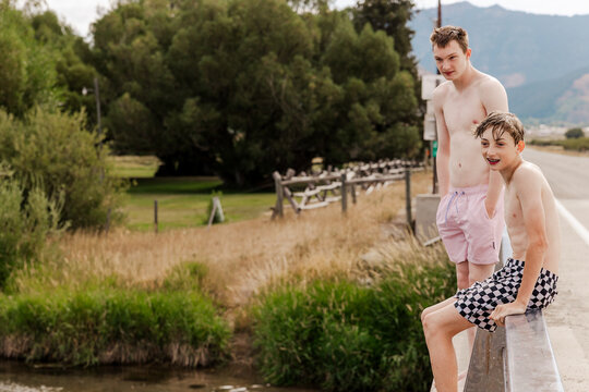 Two teenage boys hang out on a rural bridge