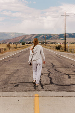 Young woman with braid walks on empty country road