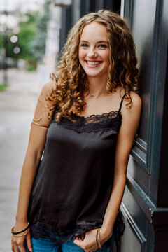 Happy teenage girl with curly hair smiling outdoors