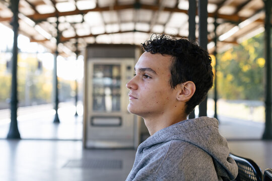 Pensive teenage boy waits on an empty train station platform
