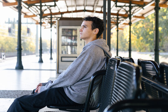 Thoughtful young man waiting for a train on a station platform