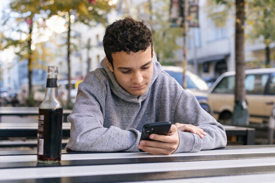 Young man scrolling on his phone outside